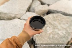 Hand holding coffee atop of rocks 4jaaW5