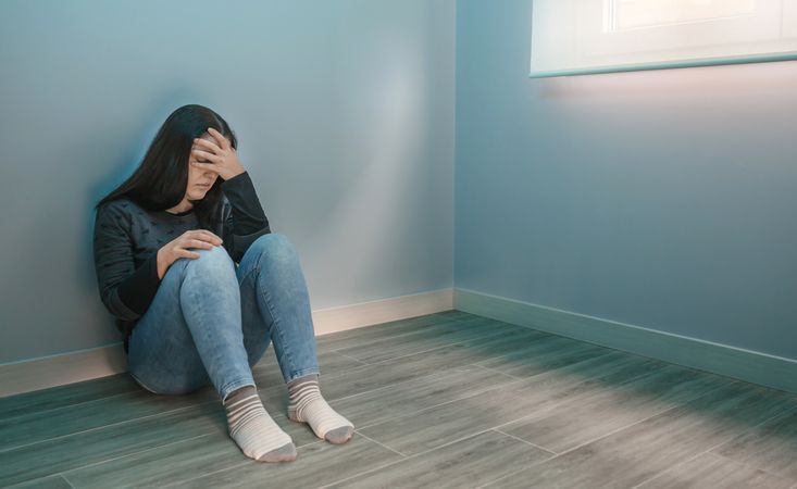 Woman overwhelmed by fatigue sitting on the floor