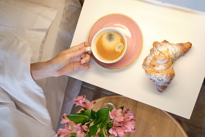 Anonymous female reaching out cup of coffee at bedside