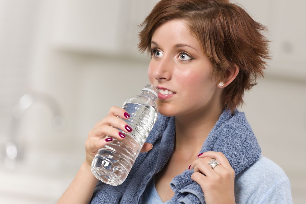 Red Haired Woman with Towel Drinking From Water Bottle