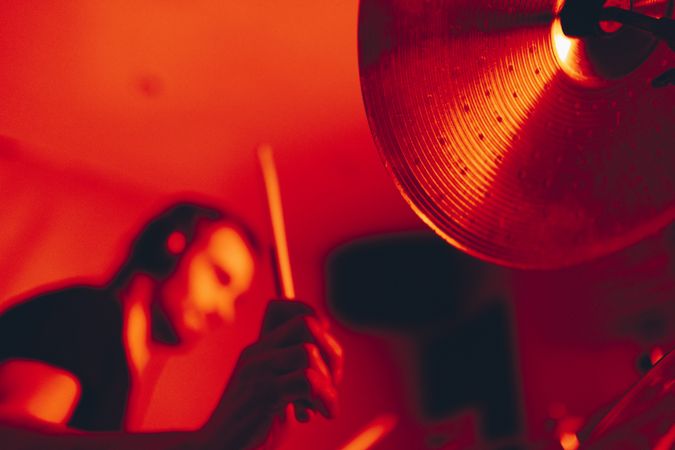 Man with drumsticks playing on drums in redness
