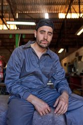 Confident male mechanic sitting on stone bench