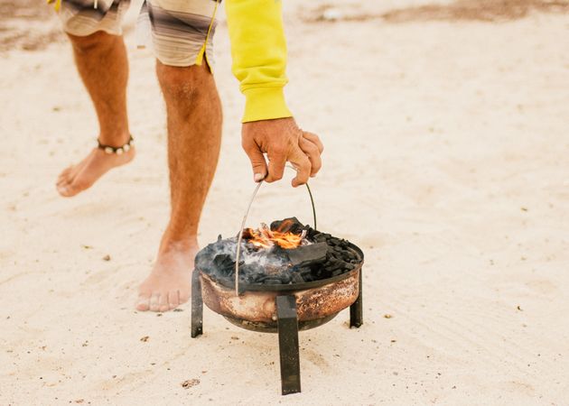 Tanned man cooking on camping stove beside parked mini van