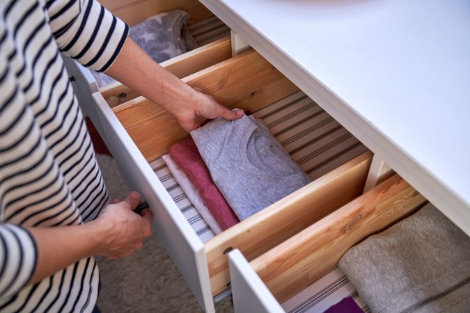 Crop person with clothes at home