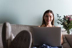 Smiling woman with laptop on couch at home