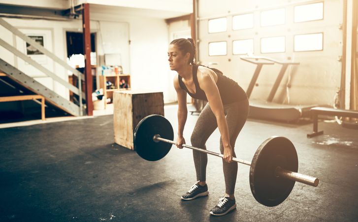 Woman performing deadlifts in bright gym