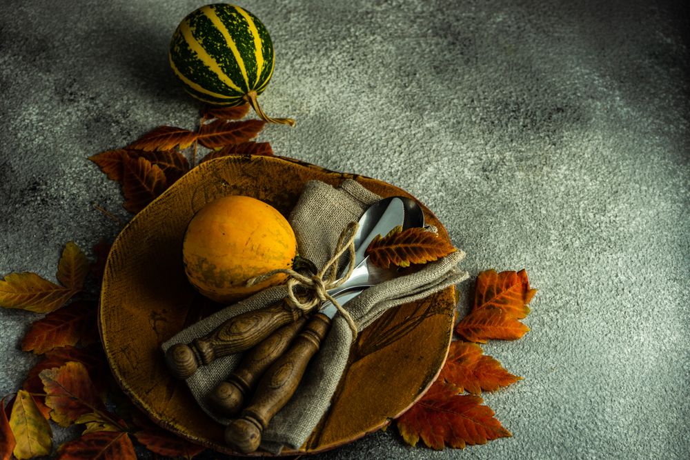 Ceramic brown plate in autumnal table setting with gourds and leaves