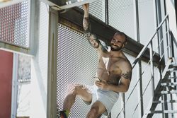 Cheerful sportsman with smartphone hanging near stairway