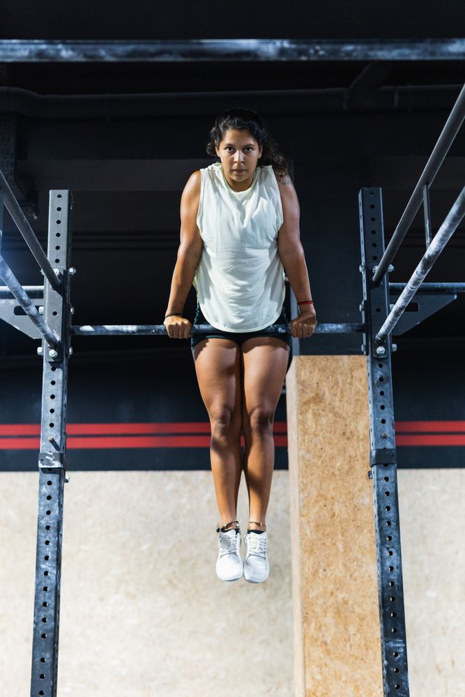 Hispanic sportswoman exercising on crossbar