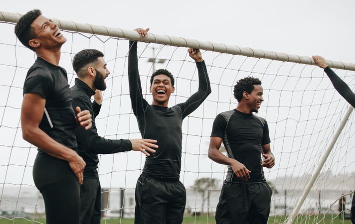 Soccer players standing near the goalpost relaxing and laughing