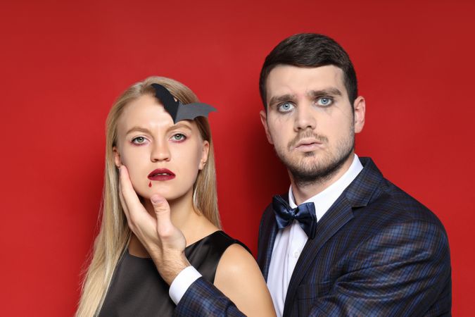 A woman and a man in Halloween costumes on a red background