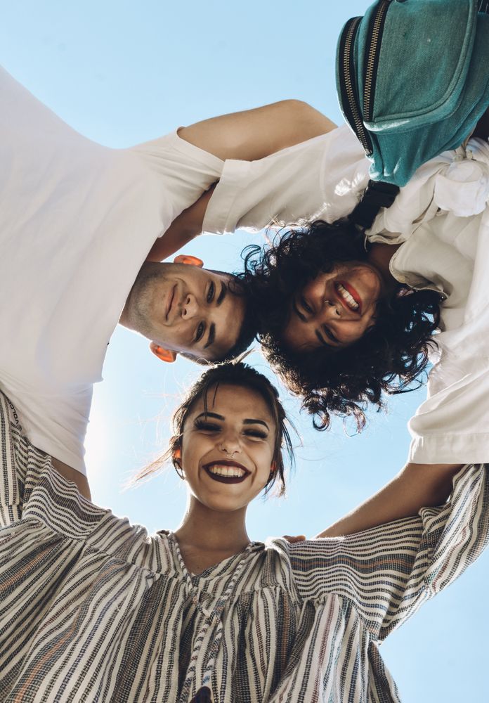 Group of friends embraced and putting their hands together.