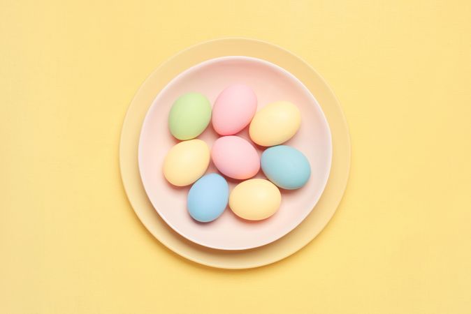 Colorful pastel eggs in bowl  on yellow background