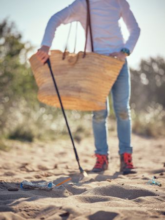Crop preteen boy seeking plastic waste with trash grabber