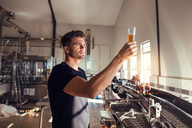 Young man examining quality of craft beer at brewery
