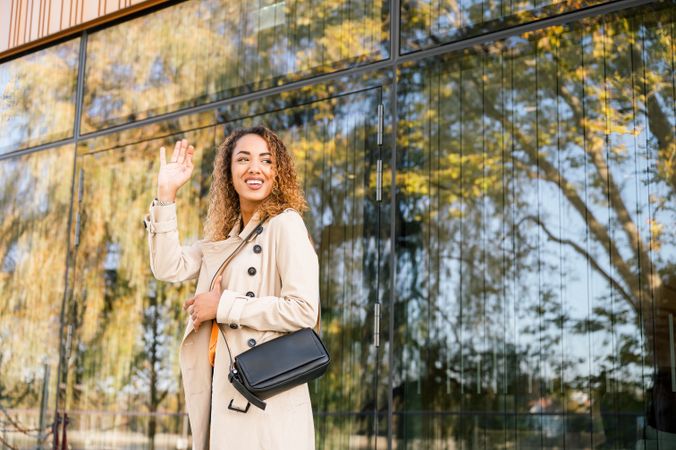 Cheerful woman standing near glass building and looking at distance