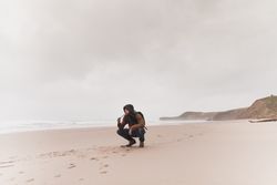 Man smoking pipe on sand shore near water