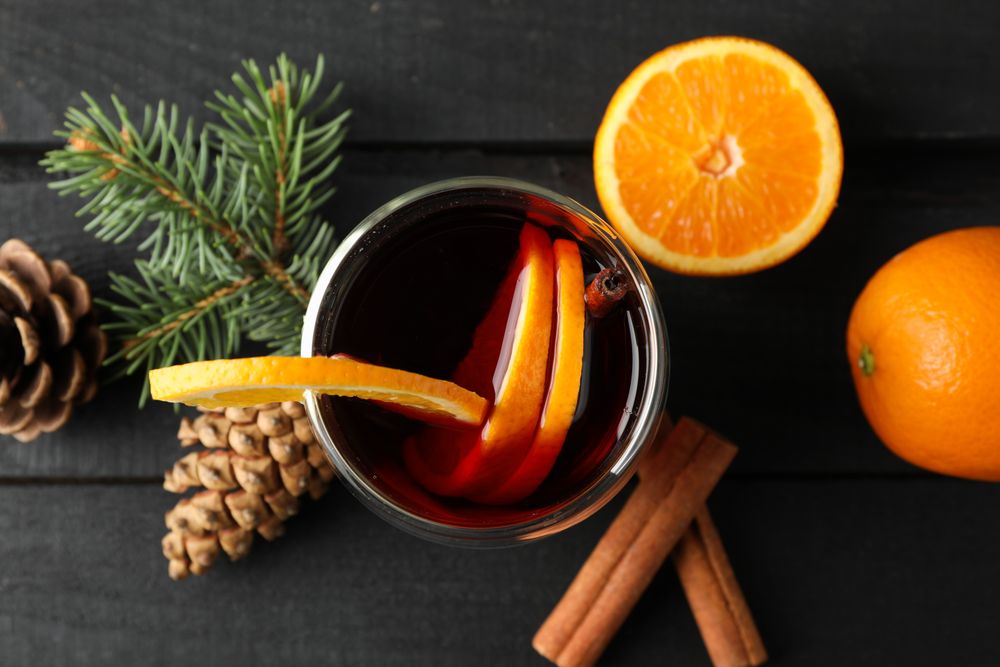 Glass of tasty mulled with orange on decorated background, top view