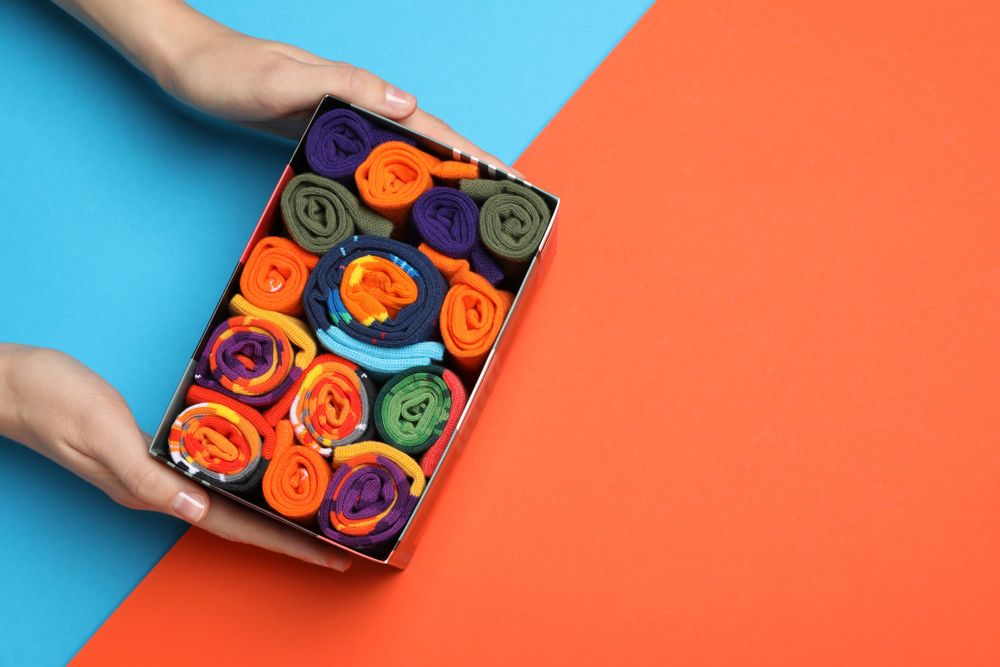 Bright socks with a print, in a box with a hand.