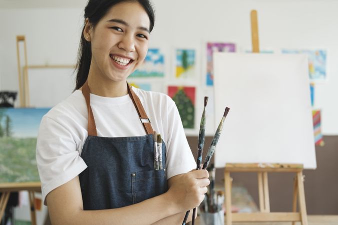 Young Asian female artist in art studio look at camera and smiling.