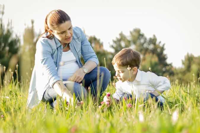Pregnant mother and son picking flowers in a field