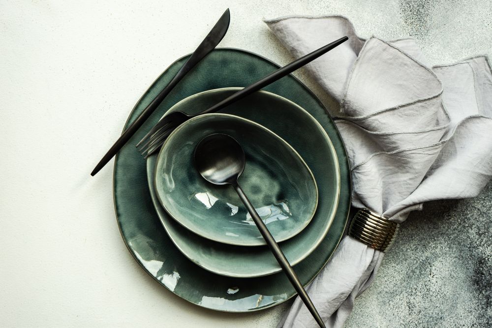 Top view of full table setting with bowls and plates on grey background