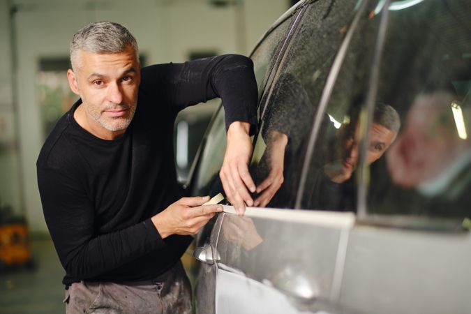 Mechanic putting protective tape on car