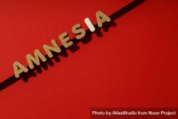 Cork letters of the word “Amnesia” with pill on red background with copy space 5l8Oo5