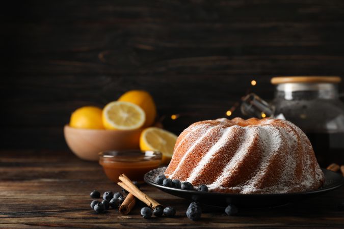 Cake with powder sugar and blueberry on wooden background, space for text
