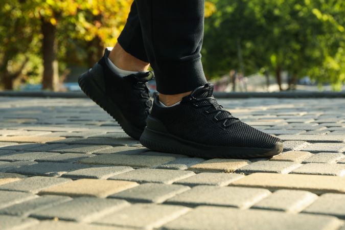 Man in sneakers and sweatpants is running in park