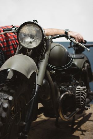 Crop man repairing army motorcycle engine