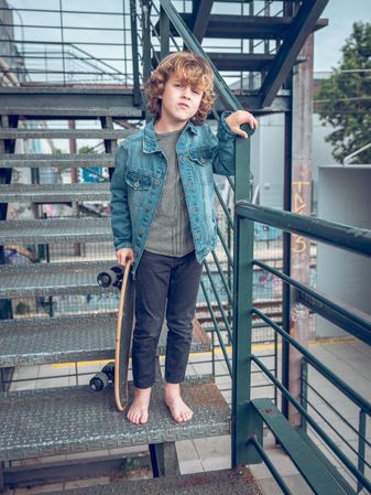 Barefoot kid with skateboard on staircase
