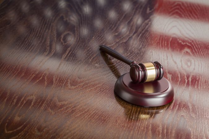 Wooden Gavel Resting on Flag Reflecting Table