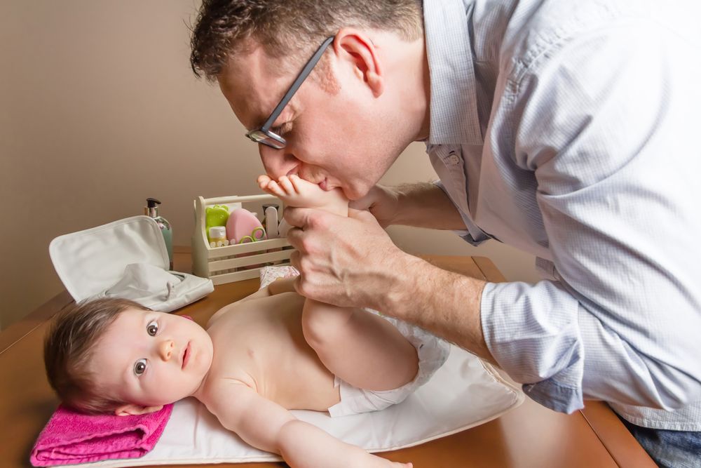 Father kissing feet of baby during diaper change