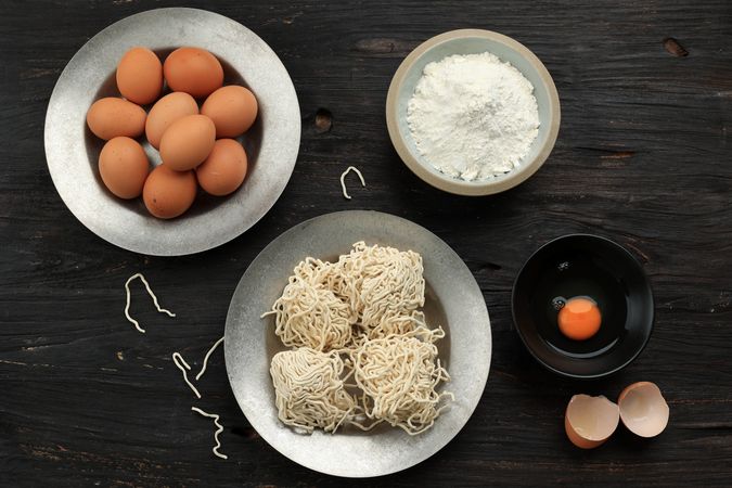Top view of egg noodles and ingredients on table