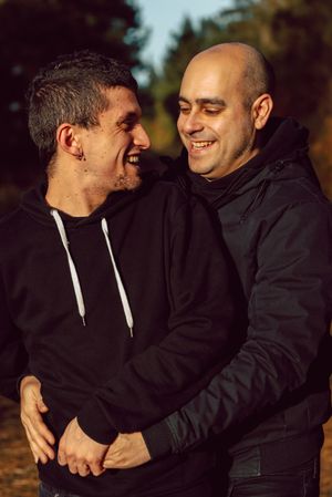 Smiling men hugging on path in park
