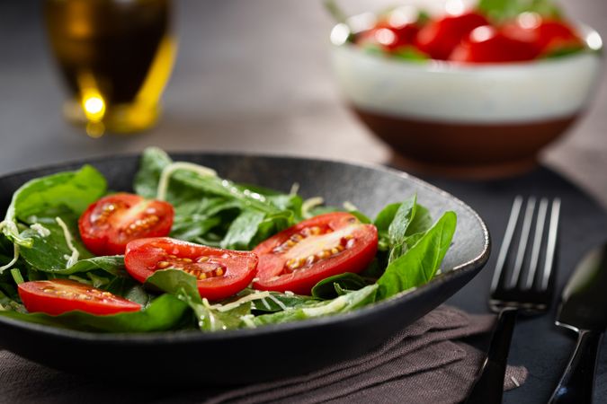 Side view of tomato and spinach salad served in dark bowl
