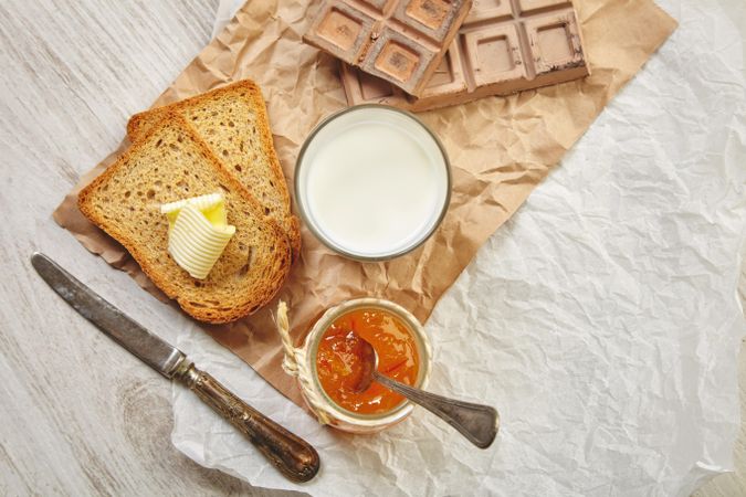 Buttered toast with milk, chocolate, knife and jam on craft paper