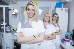 Three dental professionals in their office with arms crossed