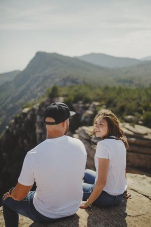 Happy couple sitting at mountain cliff