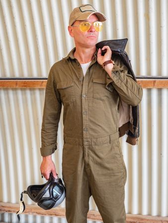 Confident pilot beside retro plane in hangar
