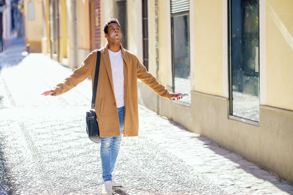 Cuban male strolling down street while looking up with a surprised expression
