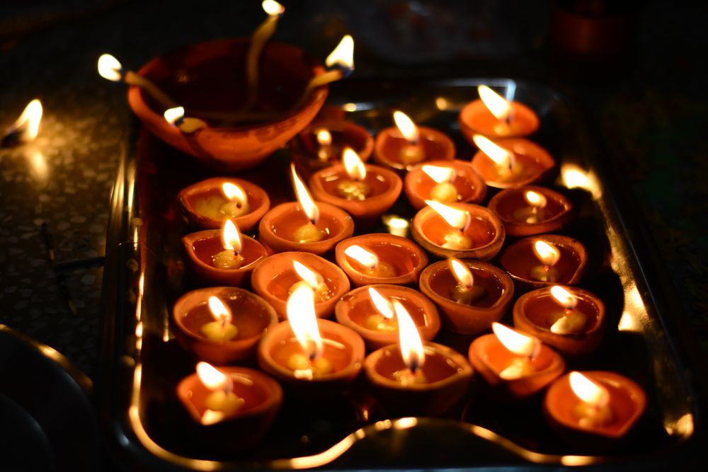 Lit diyas on tray in dark room
