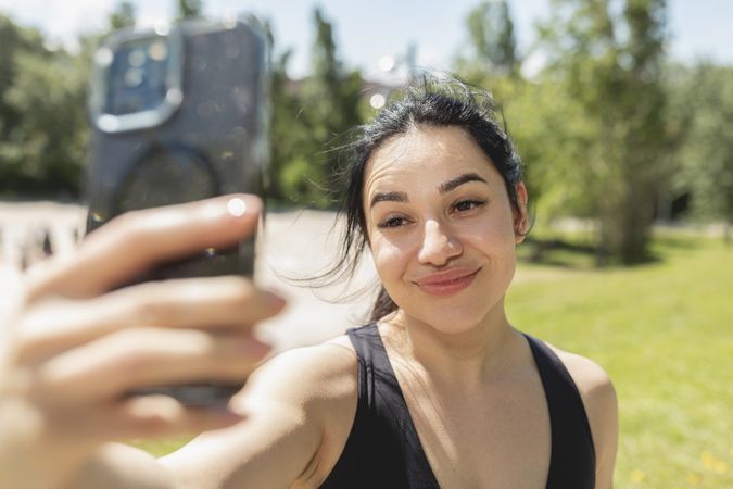 A young girl takes a selfie with her mobile phone, during a sports session in the park