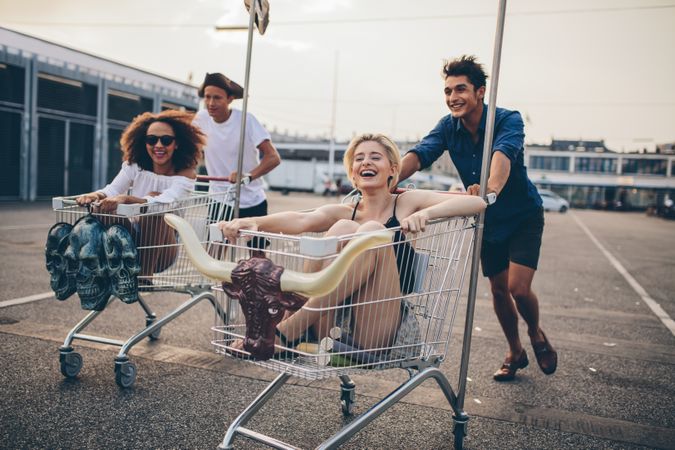 Group of friends racing with shopping carts on road