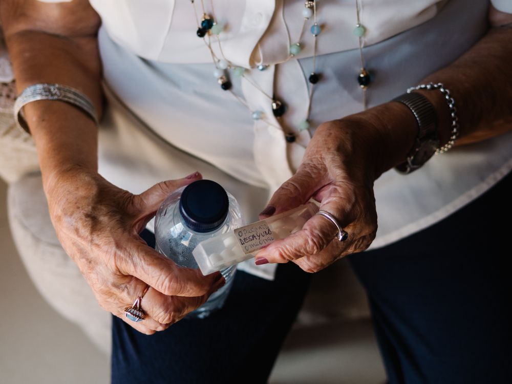 Mature female drinking medicines with water at home