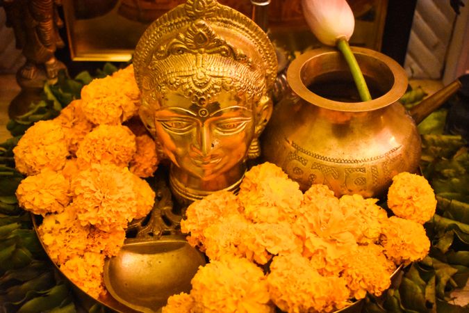 Tray of marigold flowers beside Buddha golden statue