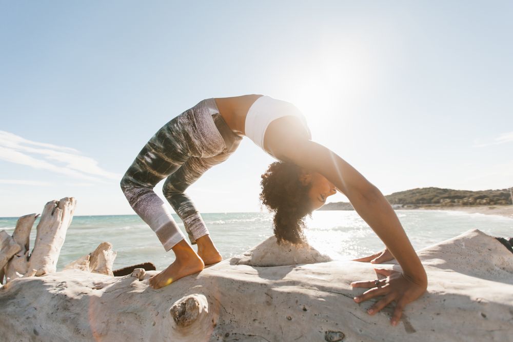 Sportive woman performing yoga posture on stones in nature