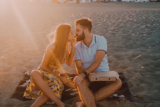 Lovely couple eating together at sandy beach