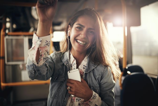 Portrait of woman smiling holding phone on public transport